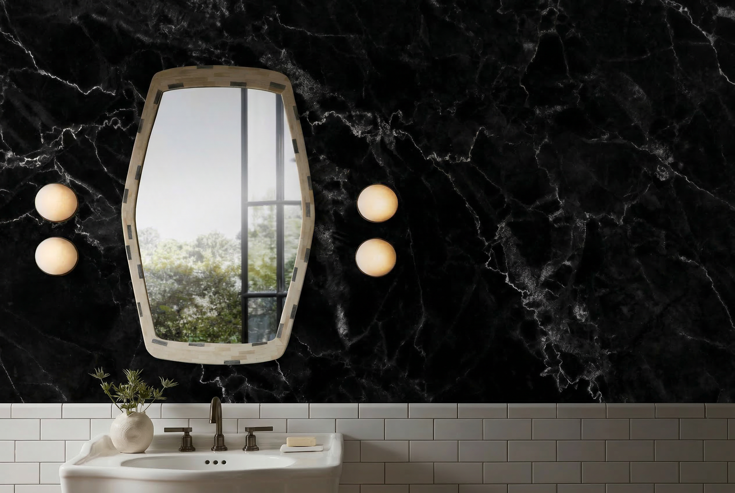 Bathroom with black marble wall, large mirror, white tile lower wall, and white sink with a gold faucet. A vase with greenery and white flowers on the sink, three circular wall lights, and a window reflected in the mirror.