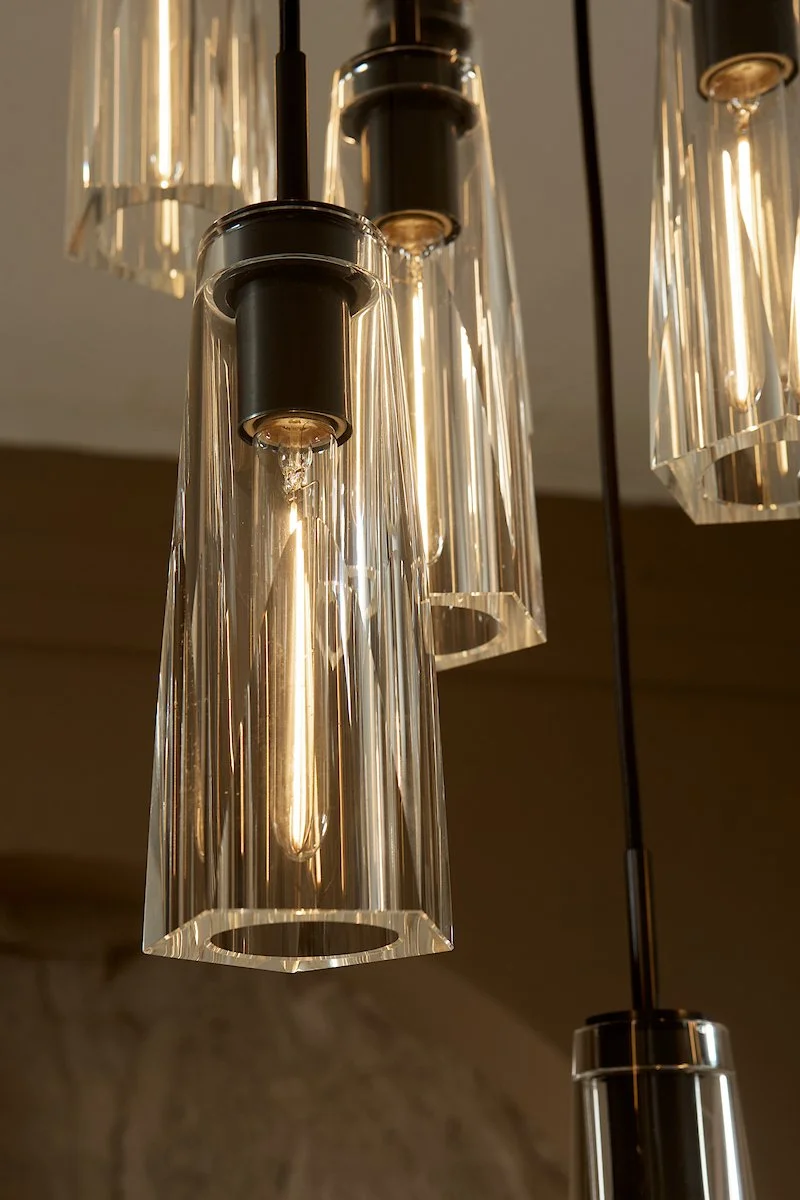 Close-up of modern pendant light fixtures with glass shades and black metal accents hanging from the ceiling.