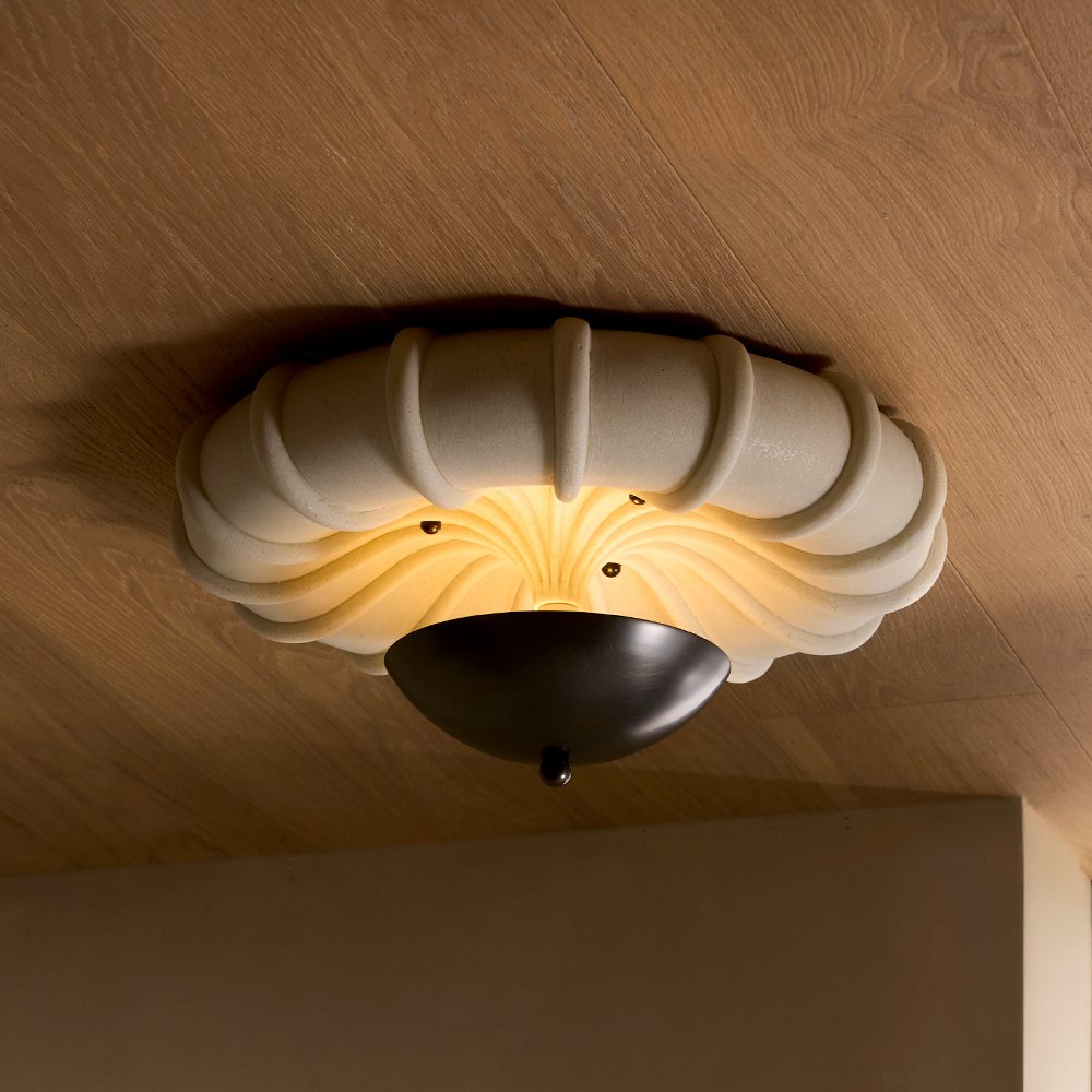 Ceiling light fixture with a beige, wavy, scalloped frame and a black half-sphere cover, mounted on a wood ceiling.