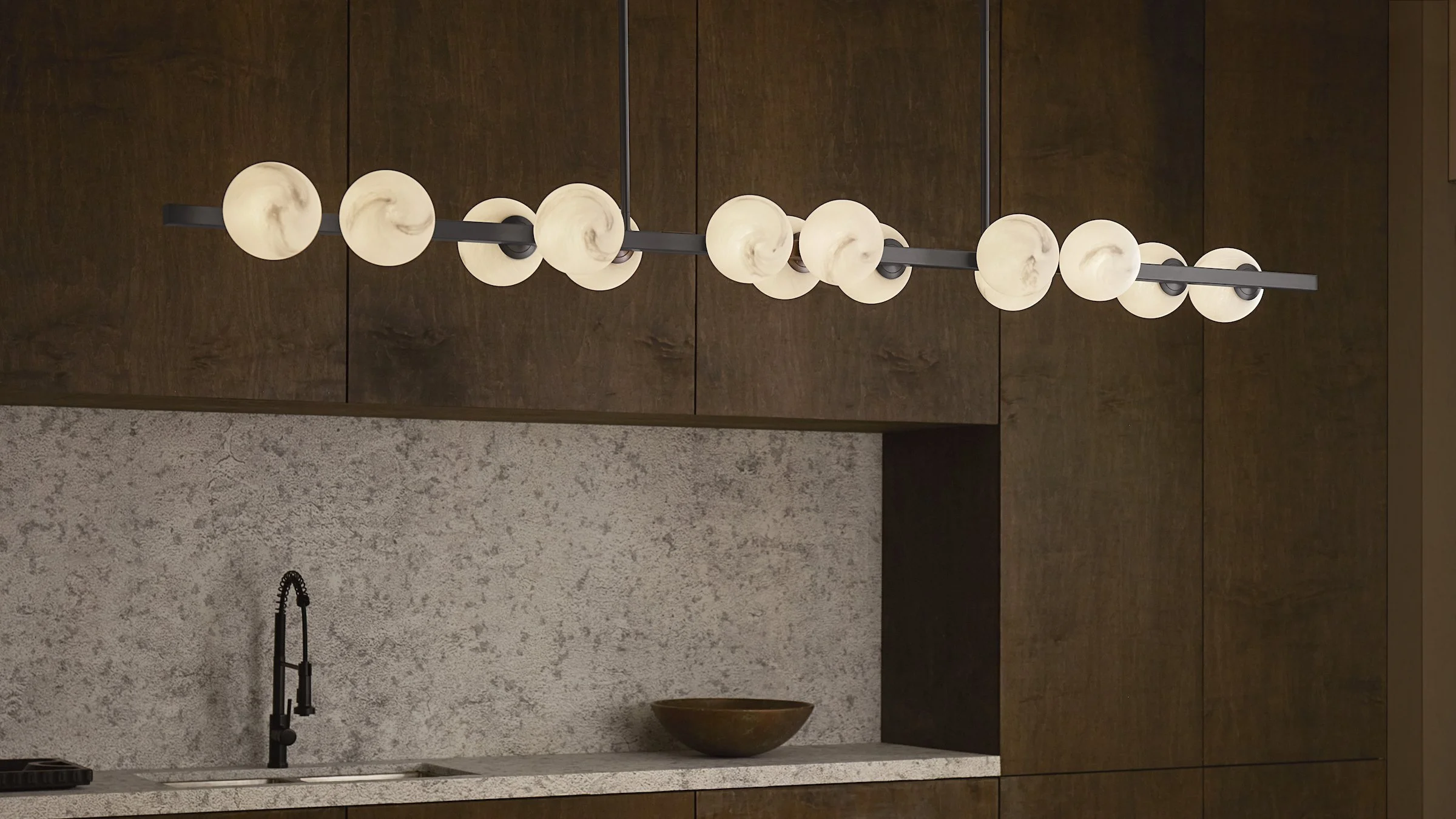 A modern kitchen ceiling light fixture with multiple round, marble-patterned glass globes mounted on black rods.