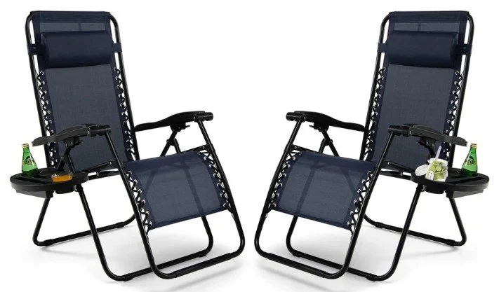 Two black outdoor lounge chairs with built-in side tables, each holding a green bottle and a flower.