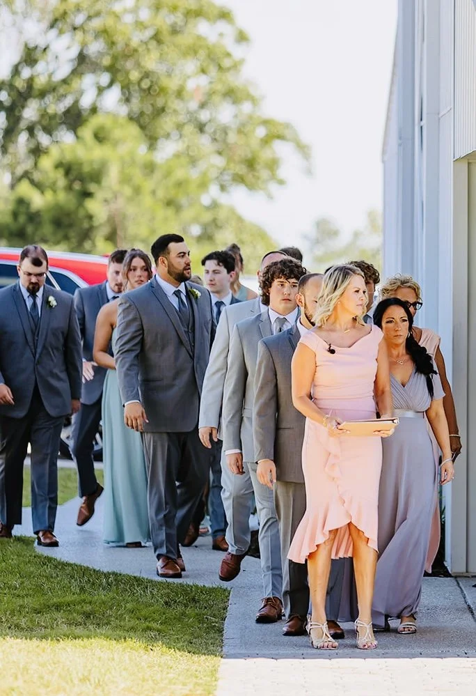 A group of people, dressed in formal attire, walking outside near a building, possibly attending a wedding or special event.
