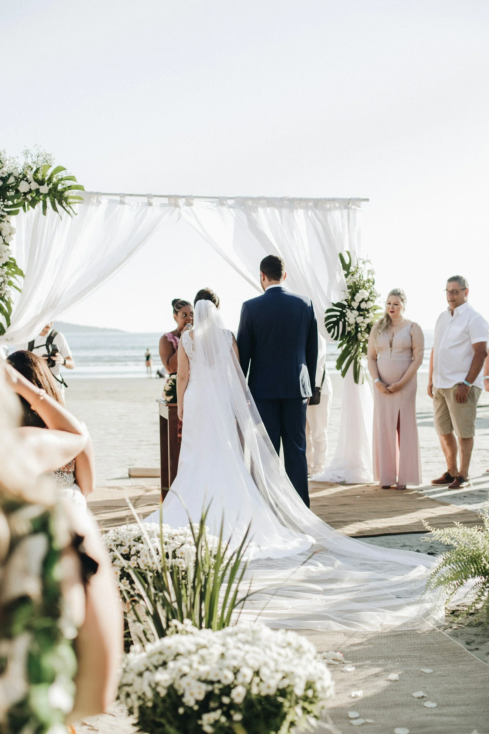 Bride and groom during a beachfront wedding ceremony with elegant floral aisle design and ocean views