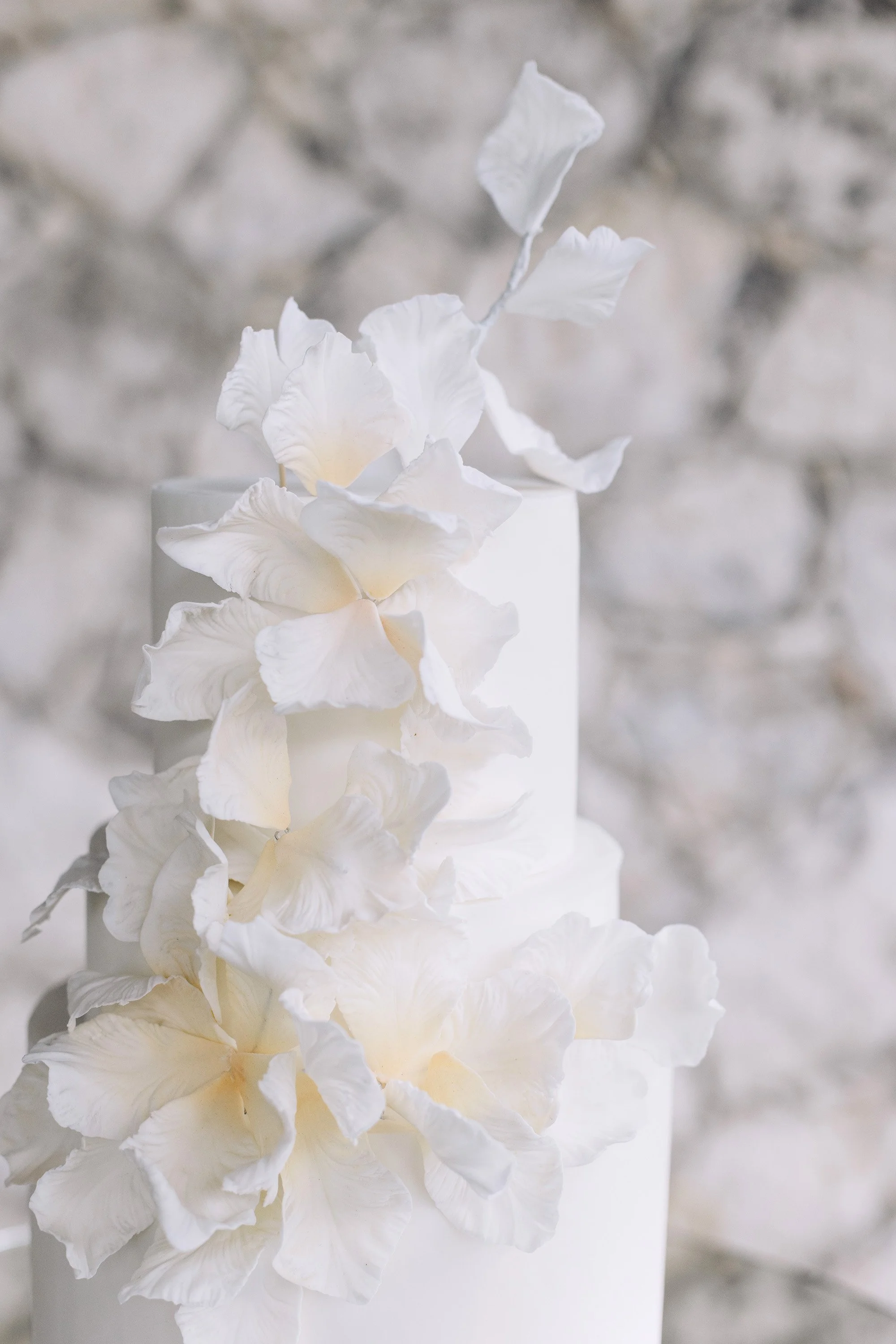 Elegant white wedding cake with sculptural floral detailing and refined minimalist wedding design styling