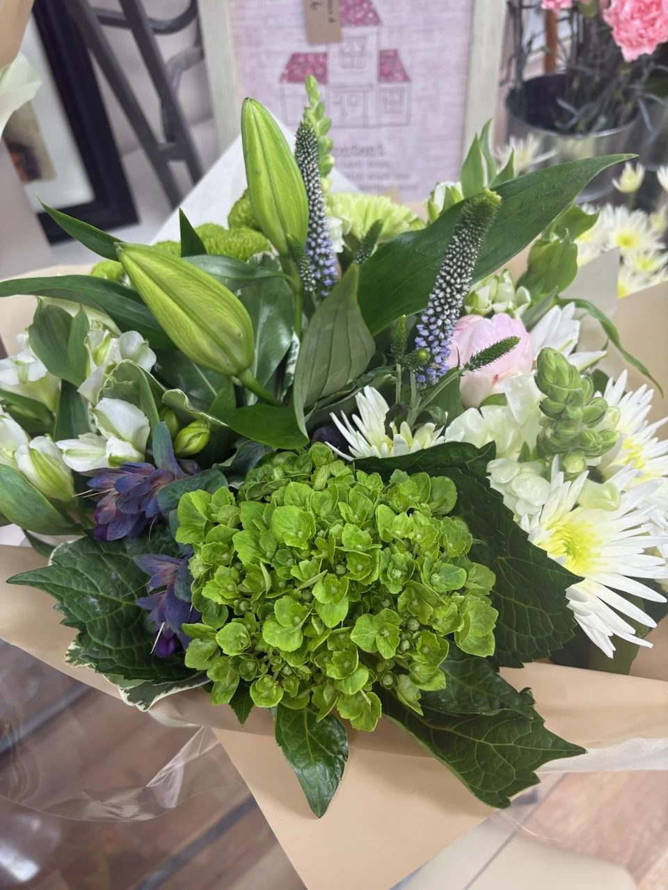 A colorful flower bouquet with lilies, daisies, hydrangeas, and greenery.