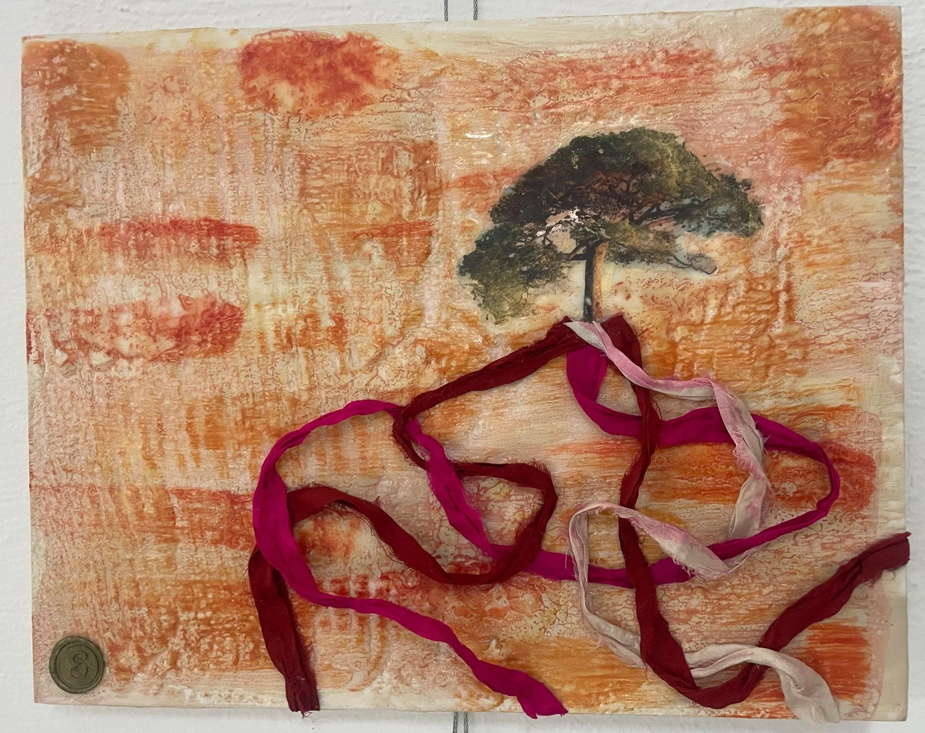 A tree with fabric roots on a red orange encaustic background.