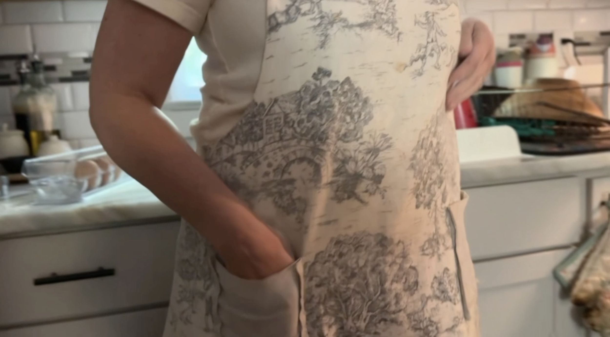 woman standing in kitchen with her hands in the pockets of her apron