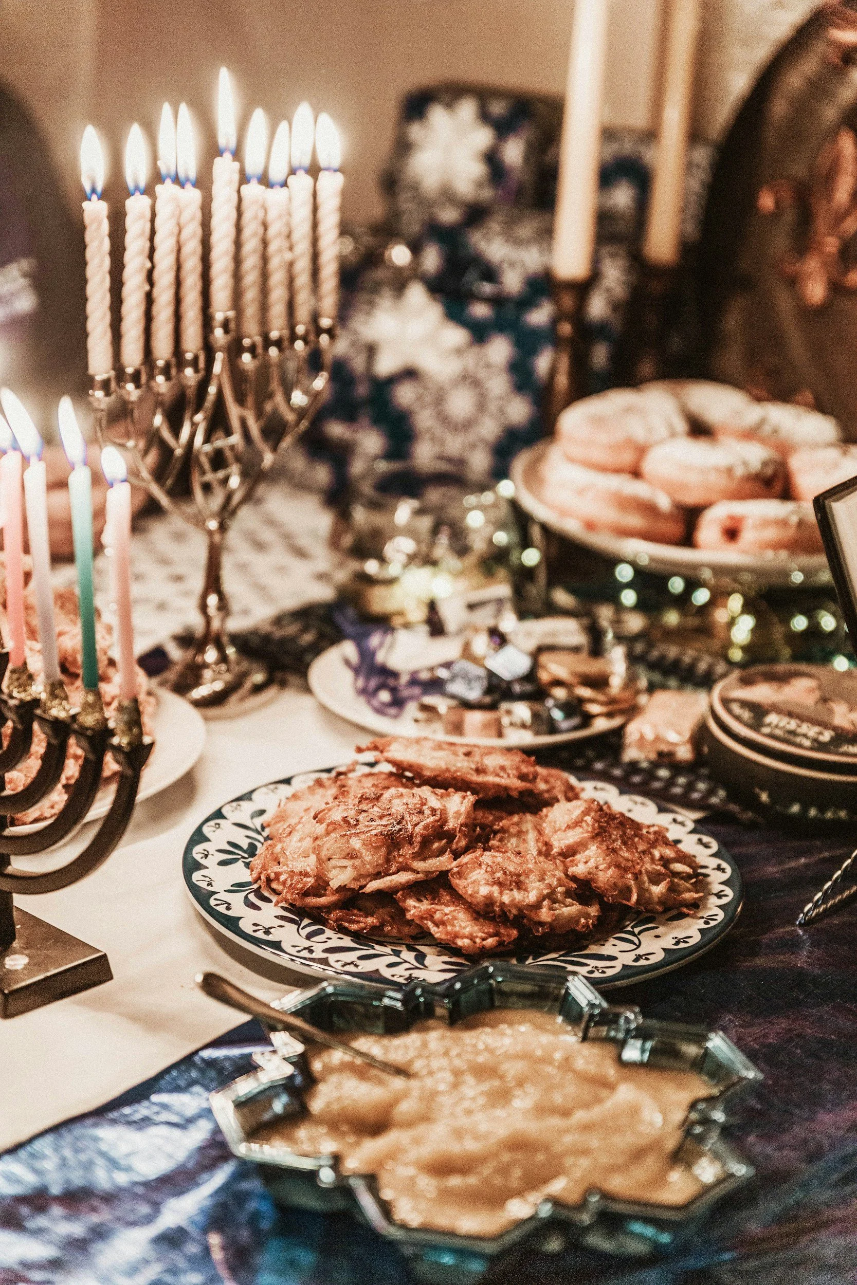 A dessert table with a menorah, donuts, and various treats, celebrating Hanukkah.