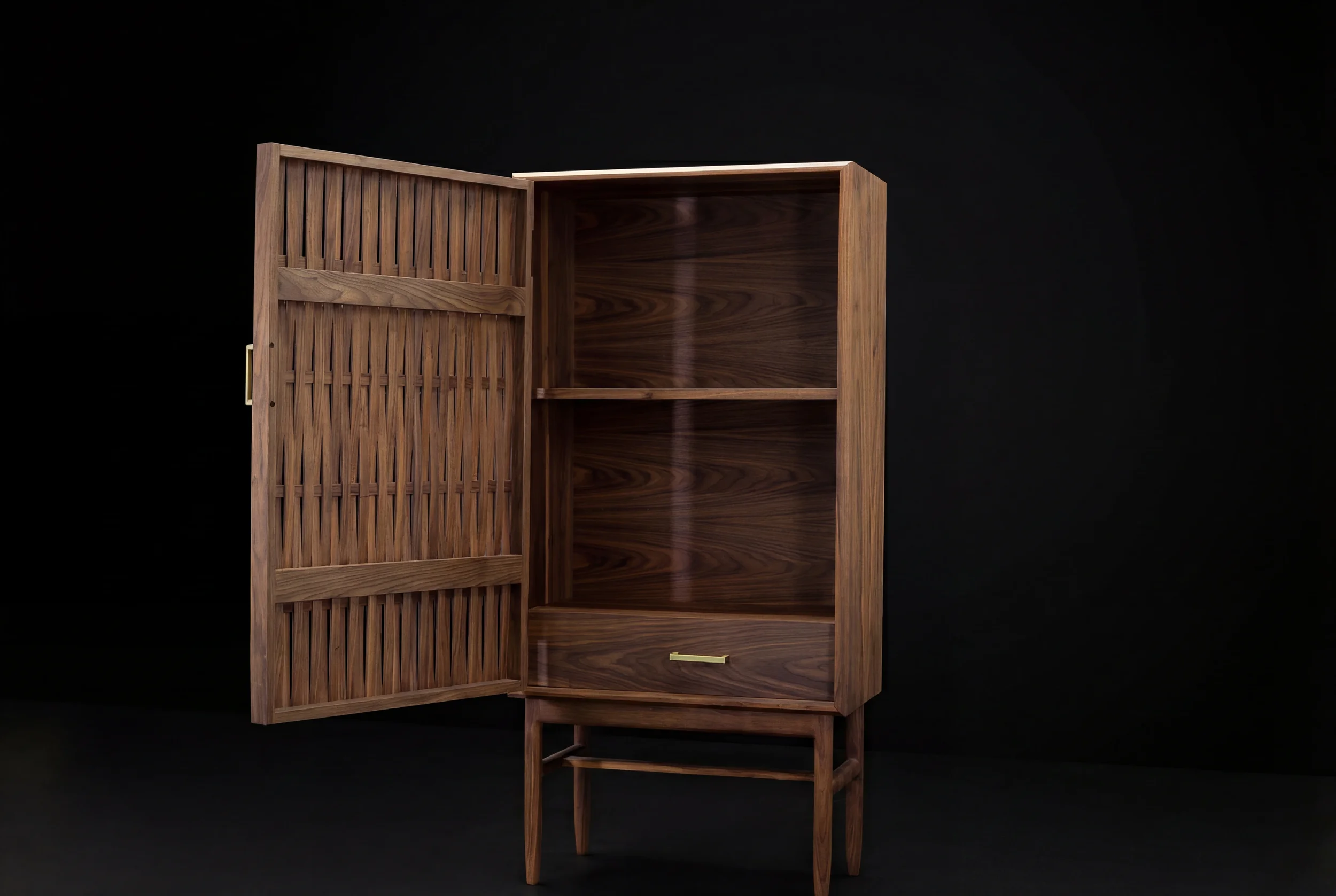 A wooden cabinet with a slatted door, open to reveal a spacious interior, set against a black background.
