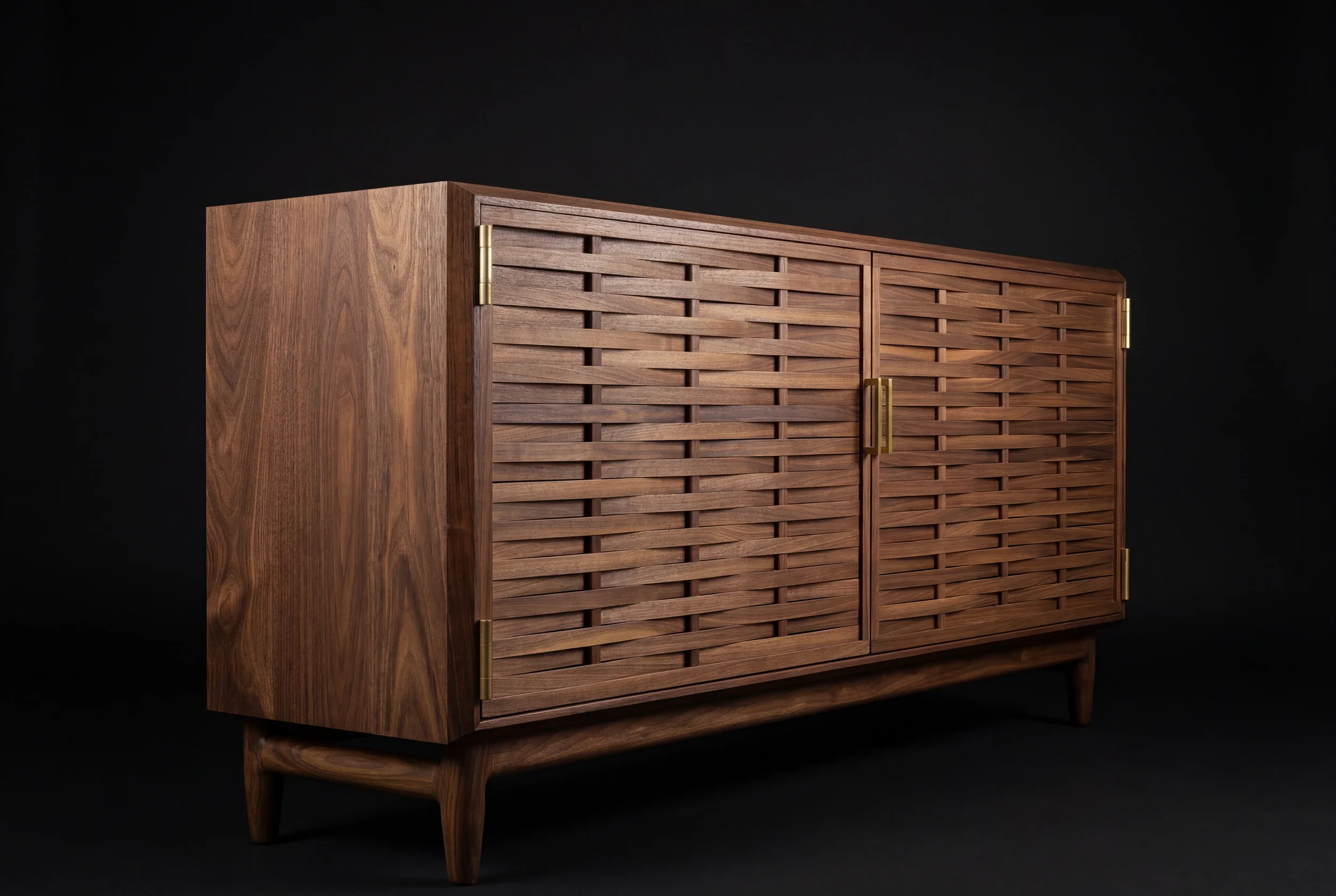 A mid-century modern wooden cabinet with a slatted front, brass handles, and tapered legs against a black background.