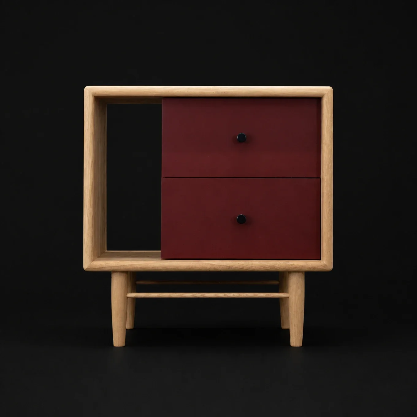 A modern wooden nightstand with two red drawers and round black knobs, set against a black background.