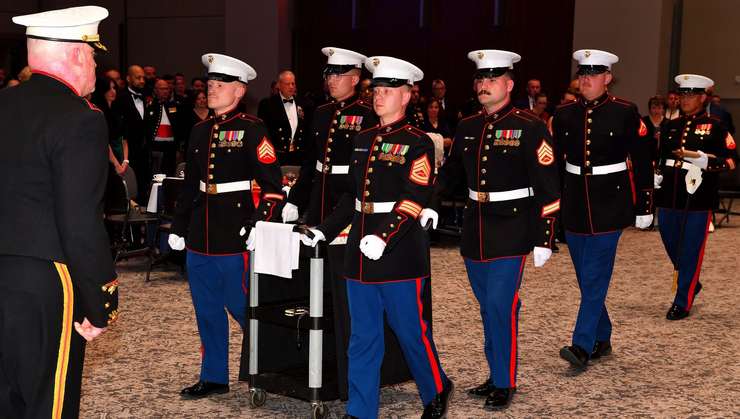Military ceremony with uniformed members of the U.S. Marine Corps standing in formation during a formal event.