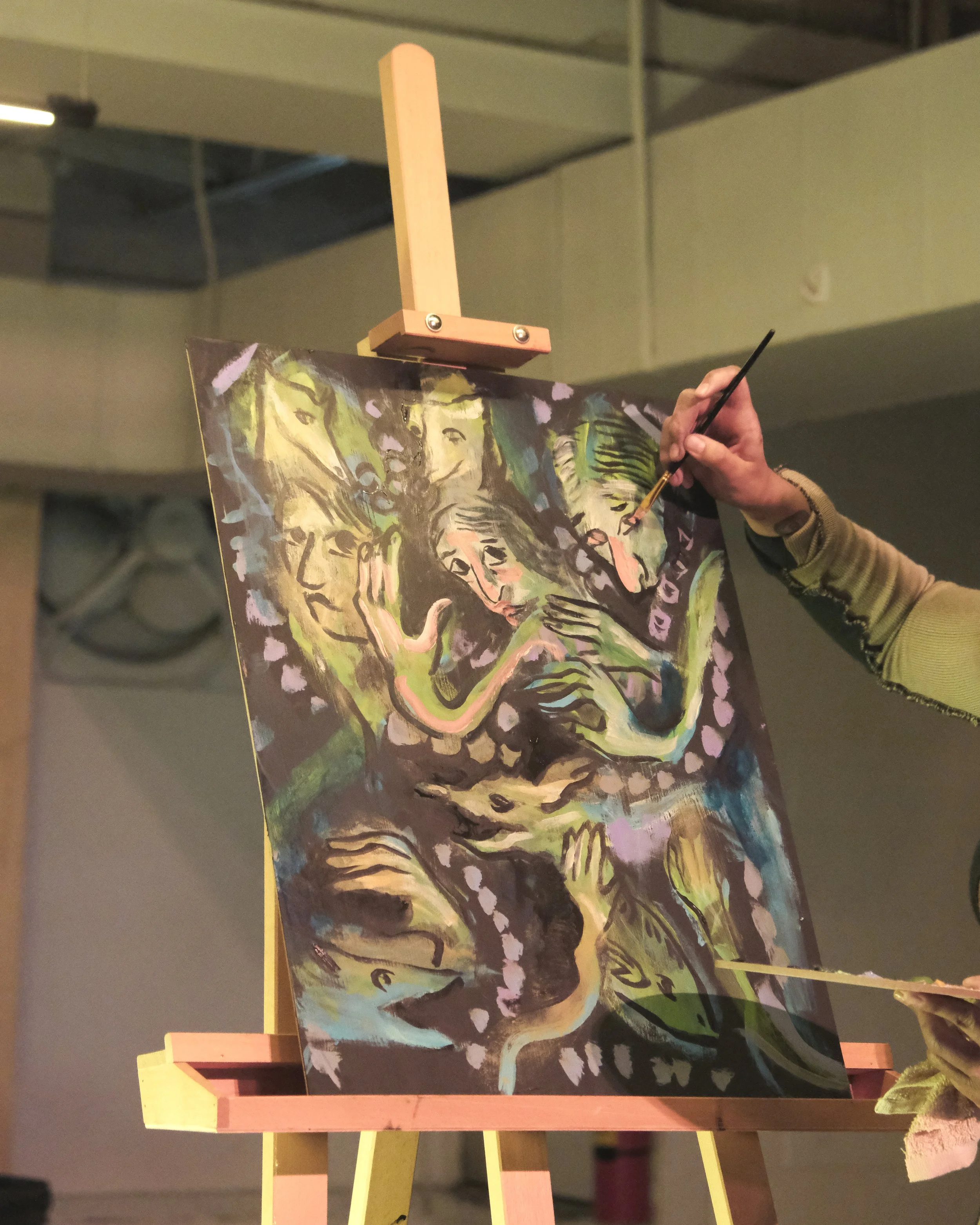 A person painting a colorful, abstract picture on a canvas, with a wooden easel and support structure.