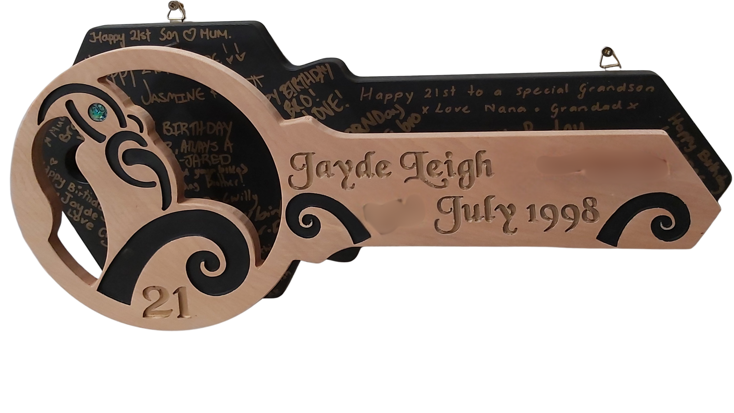 Decorative wooden car-shaped gift box with the name 'Jayde Leigh' and birthday date 'July 21, 1998' engraved on the side, featuring black and natural wood colors and intricate swirl designs. The car's wheels contain black swirls and a small decorative jewel in the center.