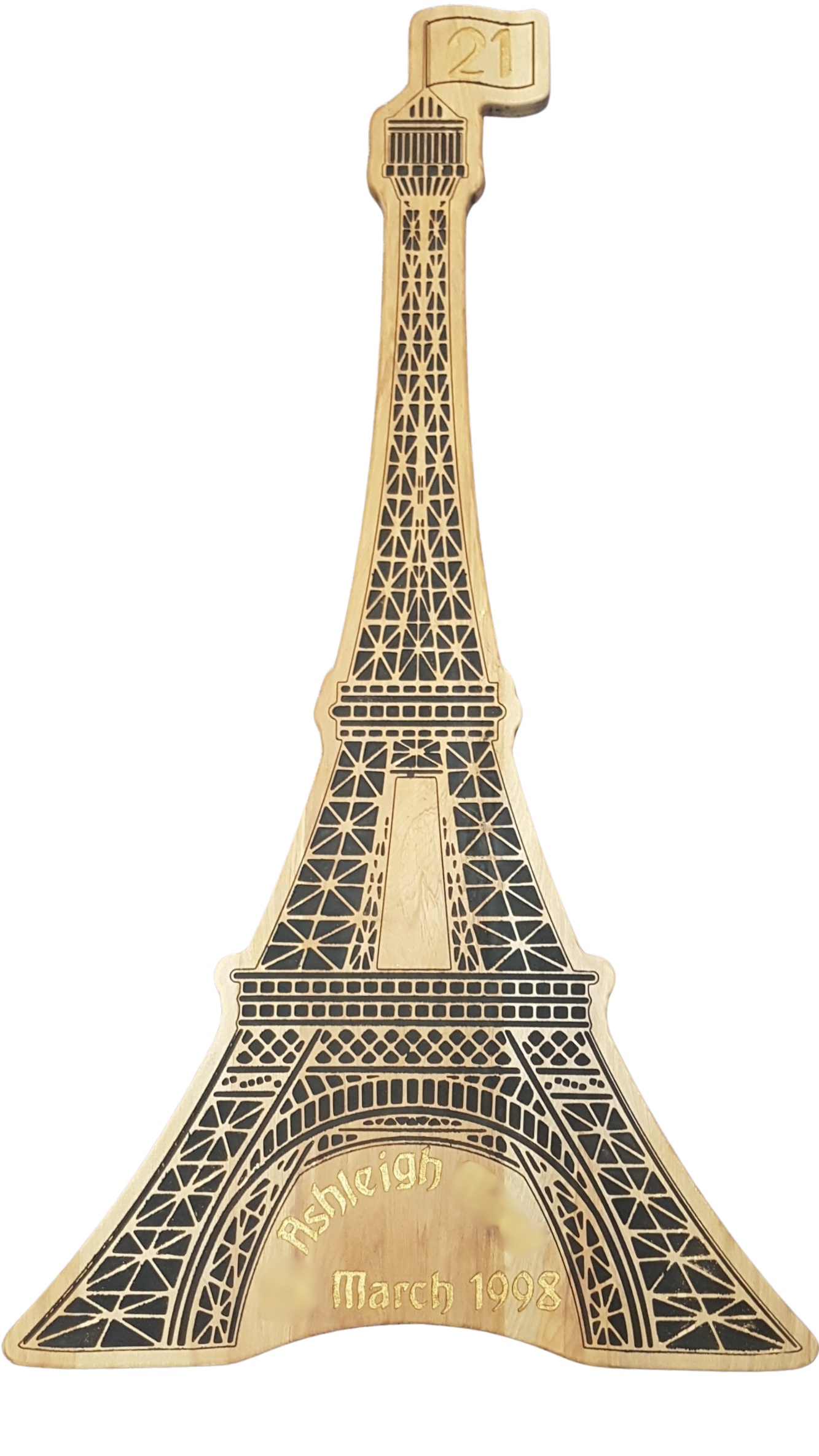 A golden souvenir plaque shaped like the Eiffel Tower with 'Resleigh' engraved at the bottom and 'March 1998' underneath.