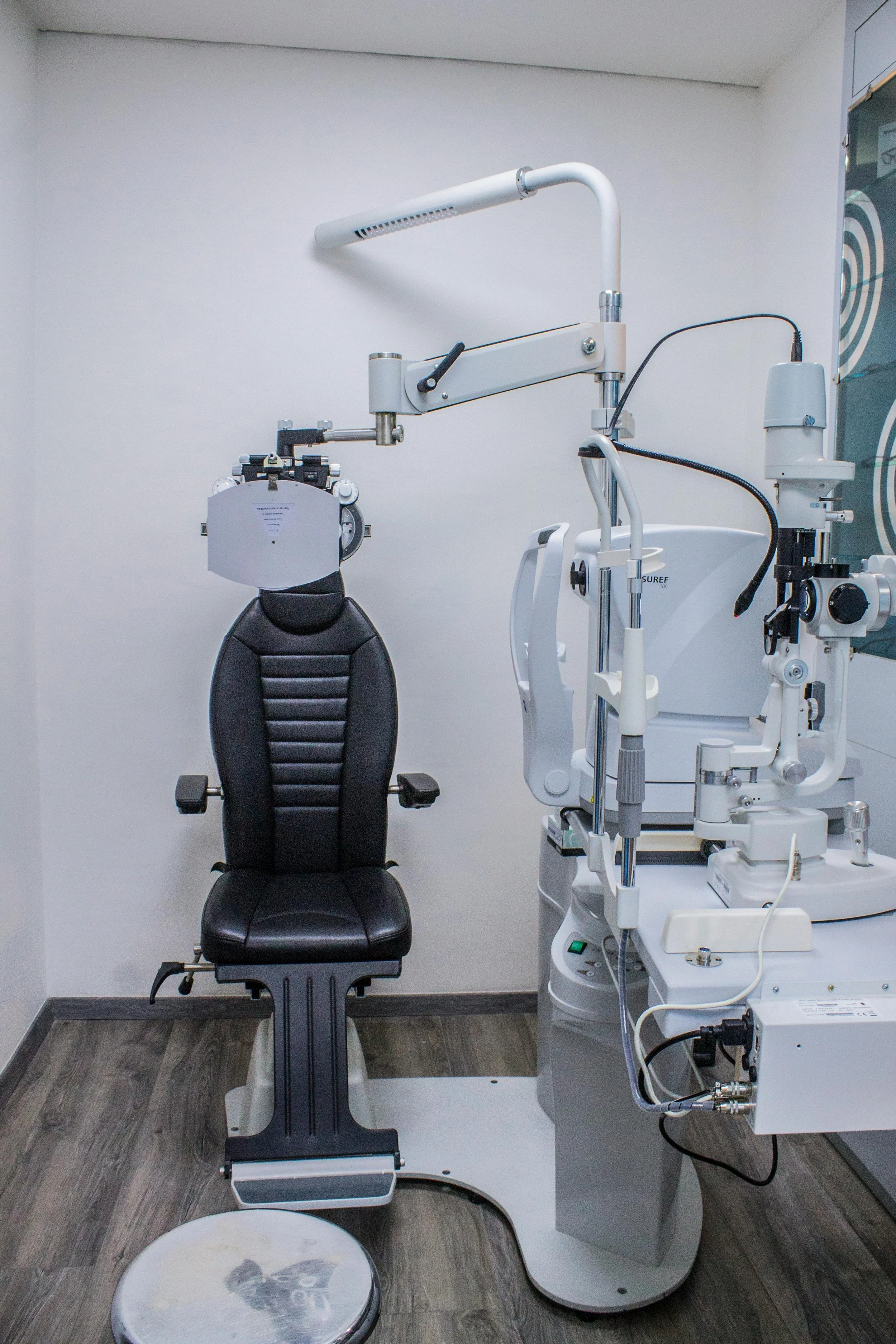 Optometry examination room with an eye examination chair and ophthalmic equipment.