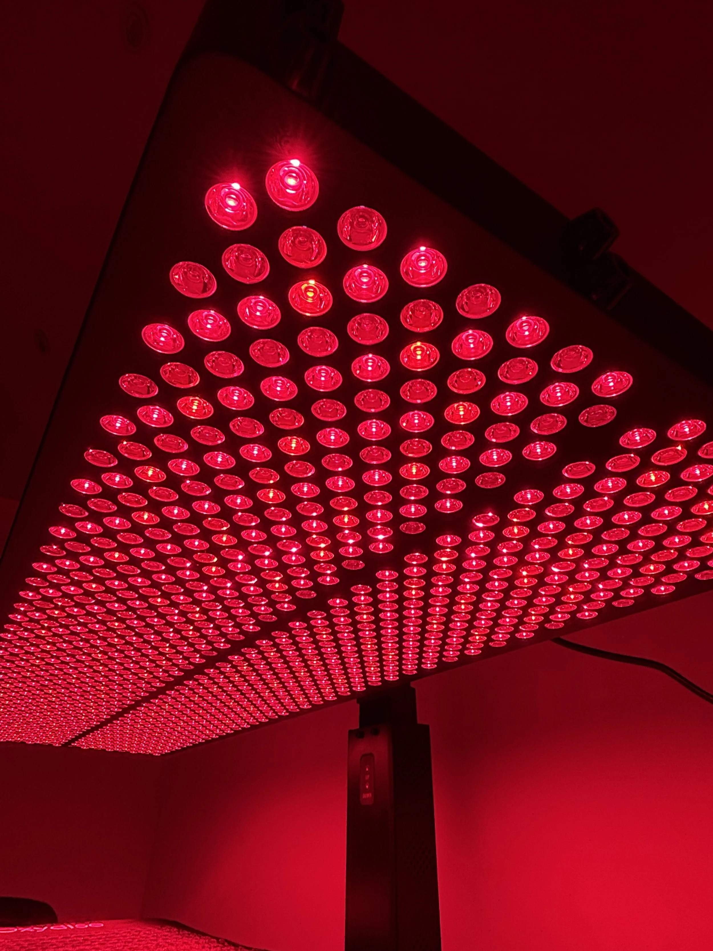 A woman walking down a spiral staircase illuminated with red lighting.