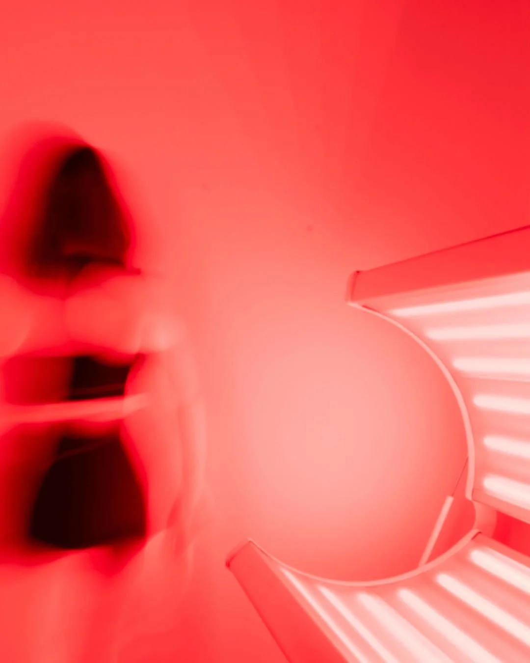 A woman with short dark hair taking a selfie in a red-lit, modern interior space with curved walls and illuminated steps.