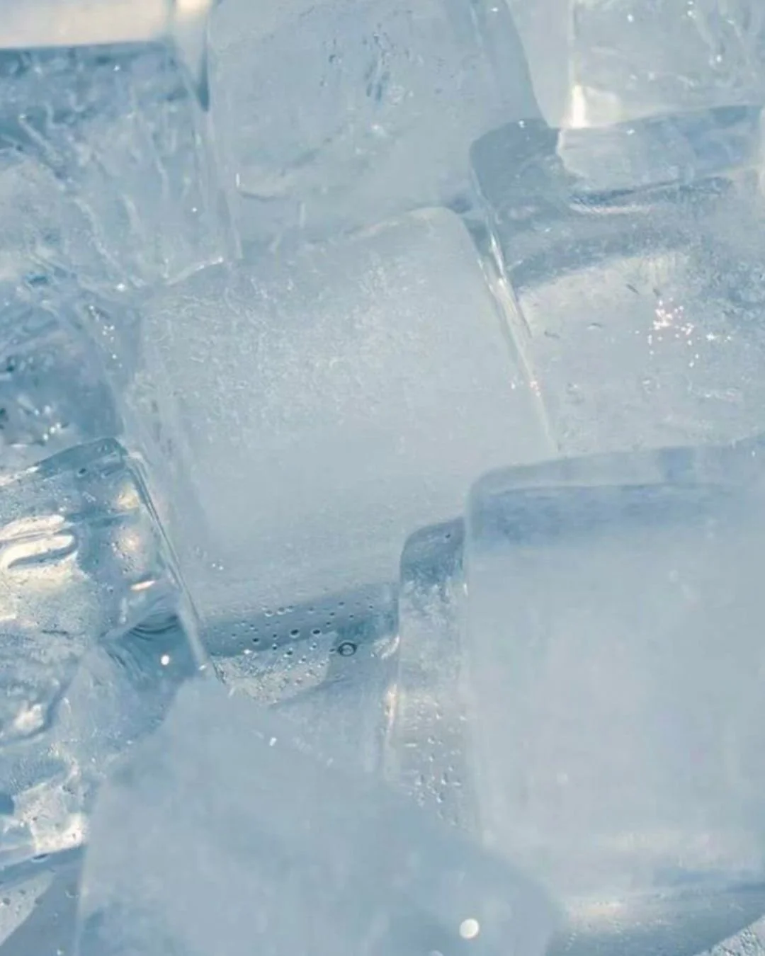 Close-up of ice cubes with condensation and bubbles.