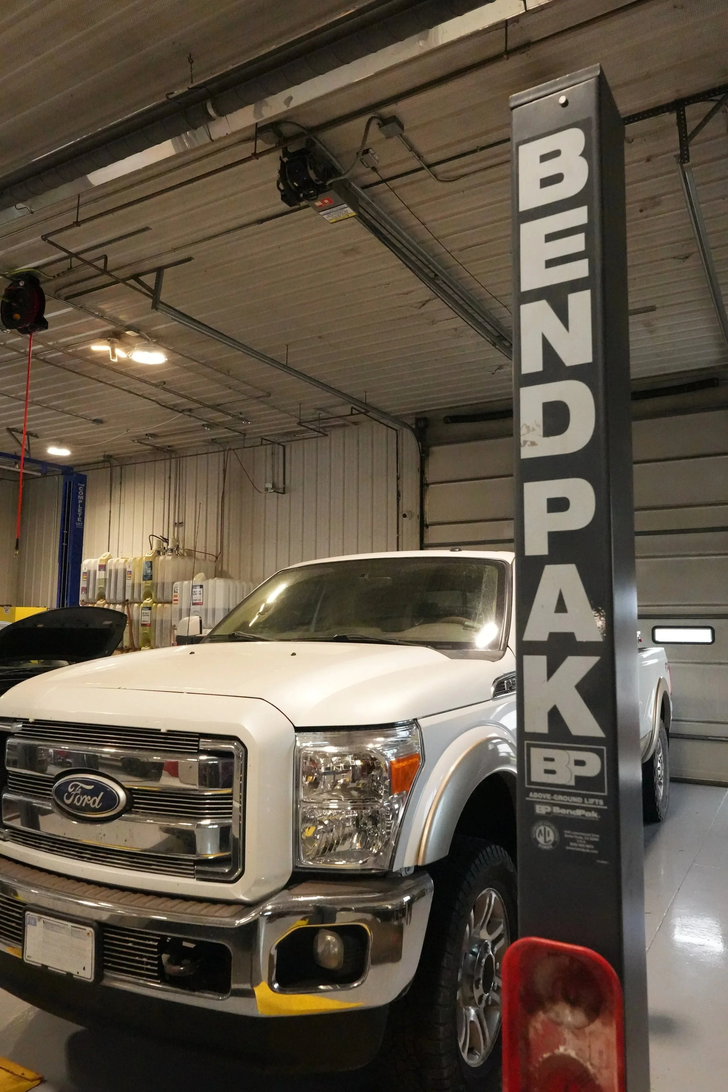 A white Ford truck parked inside a BP gas station. The truck is positioned in front of a BP price sign. The station has a gray industrial ceiling and fluorescent lighting.
