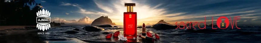 A bottle of Ajmal Sacred Love perfume placed on a rock by the ocean at sunset, with red flower petals and white stones, and the Ajmal logo and Sacred Love text with a love lock icon.