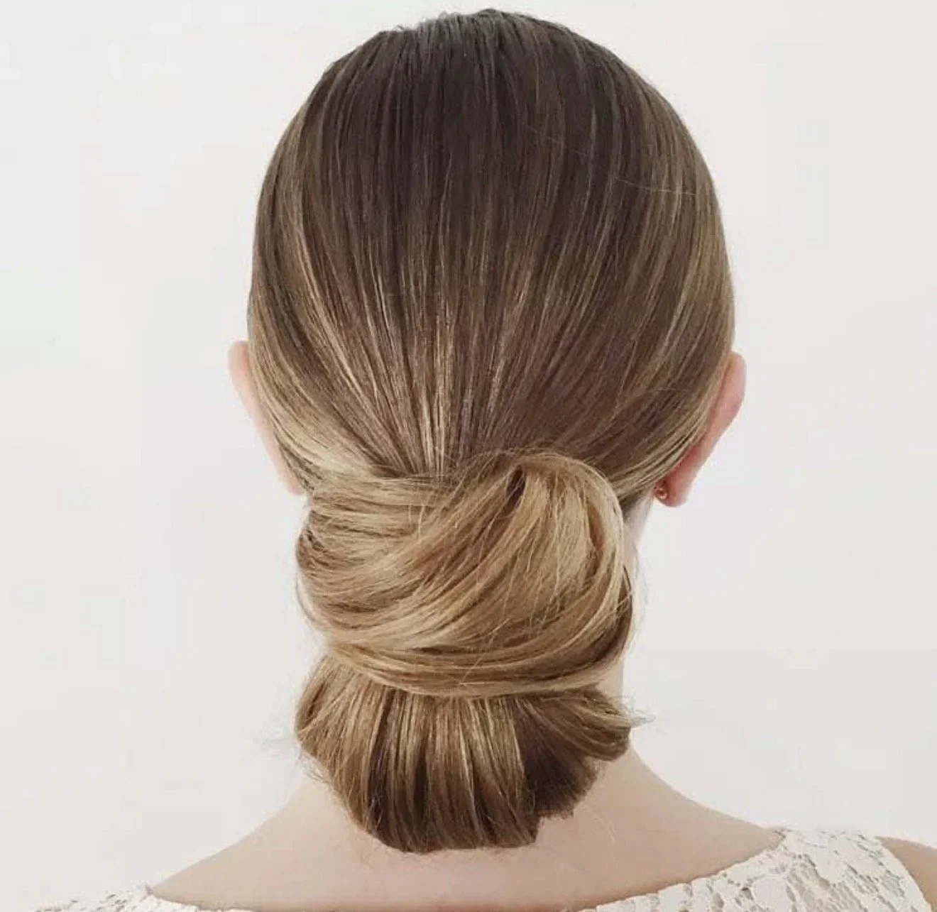 Back view of a woman with light brown hair styled in a loose, low bun.