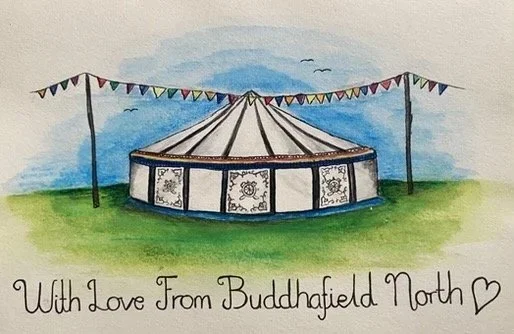 Watercolor painting of a circus tent with colorful bunting, set on green grass with a blue sky and birds in the background, and the text 'With Love From Buddhafield North' with a heart symbol.