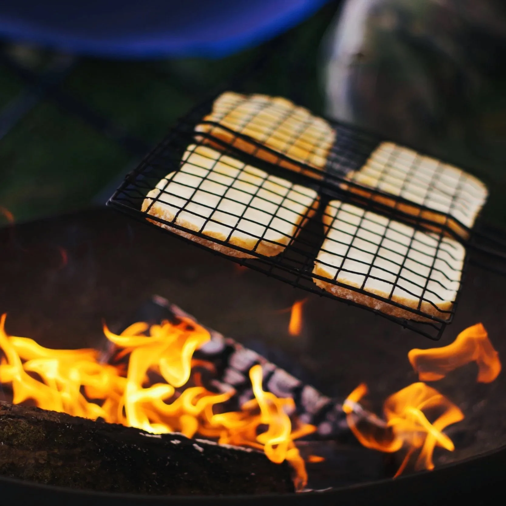Close-up of cheese slices grilling over an open flame on a barbecue grill.