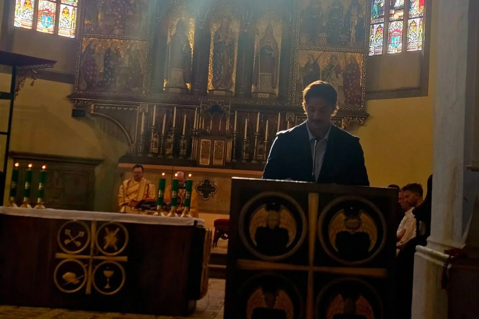 Interior of a historic church visited during the 2026 Slovakia trip, featuring an ornate altar, stained-glass windows, and a speaker at the lectern.