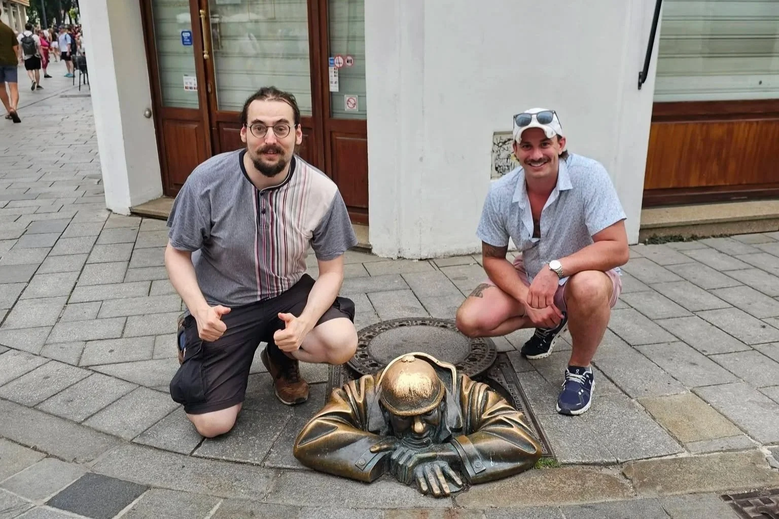 AJ Gubash and a fellow traveler posing beside a bronze street sculpture during their August 2026 travels in Central Europe.