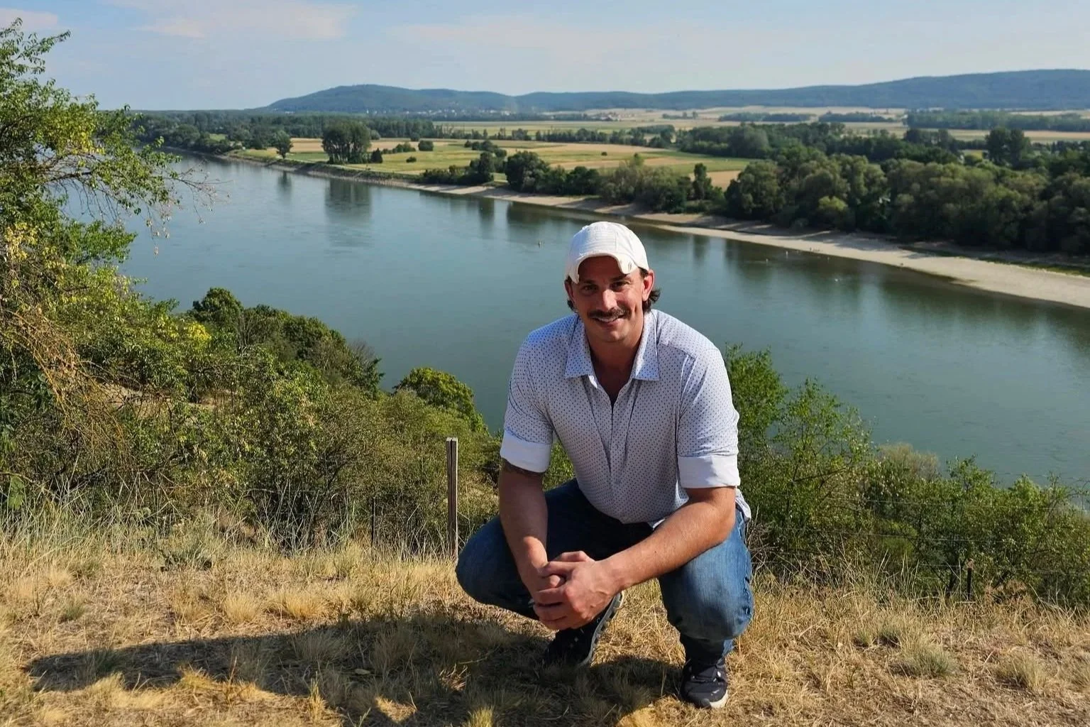 AJ Gubash overlooking a scenic river and countryside during his August 2026 visit to Slovakia.