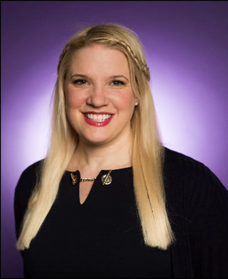 Liza Savage Katz, A woman with long blonde hair smiling against a purple background.
