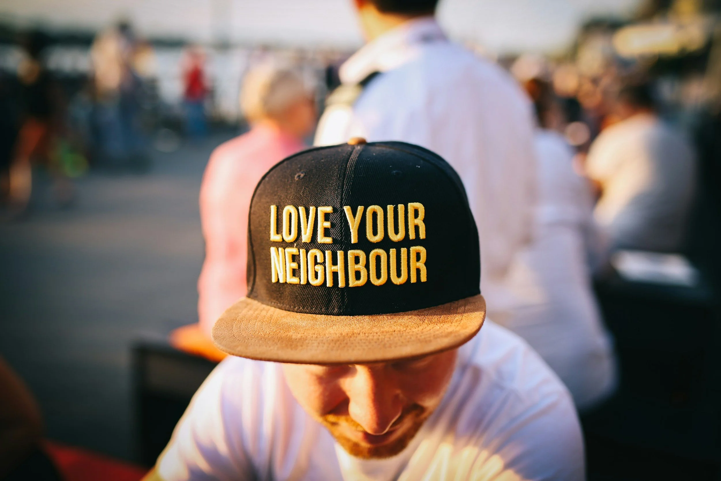 Jesus Cares - Man wearing hat that says, "Love Your Neighbor"
