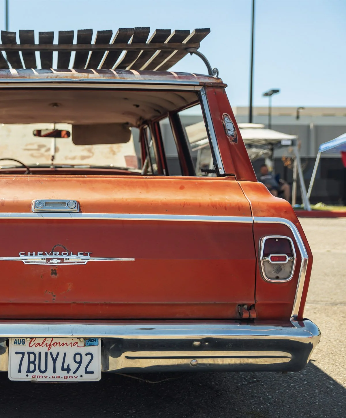 Rear view of a vintage red Chevrolet pickup truck with a weathered body and a California license plate.