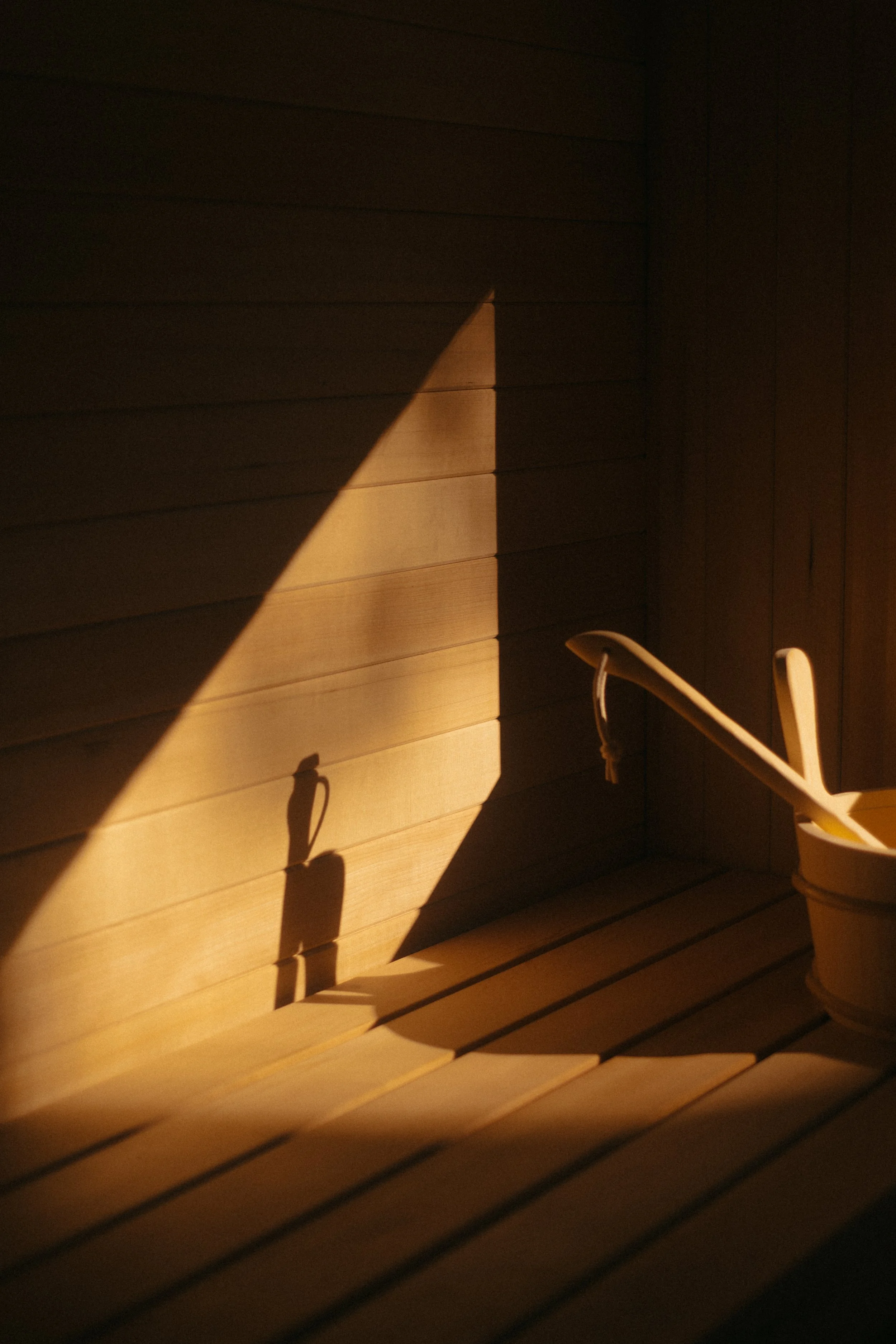 Sunlight streaming through a custom built sauna, casting shadows on a wooden wall.