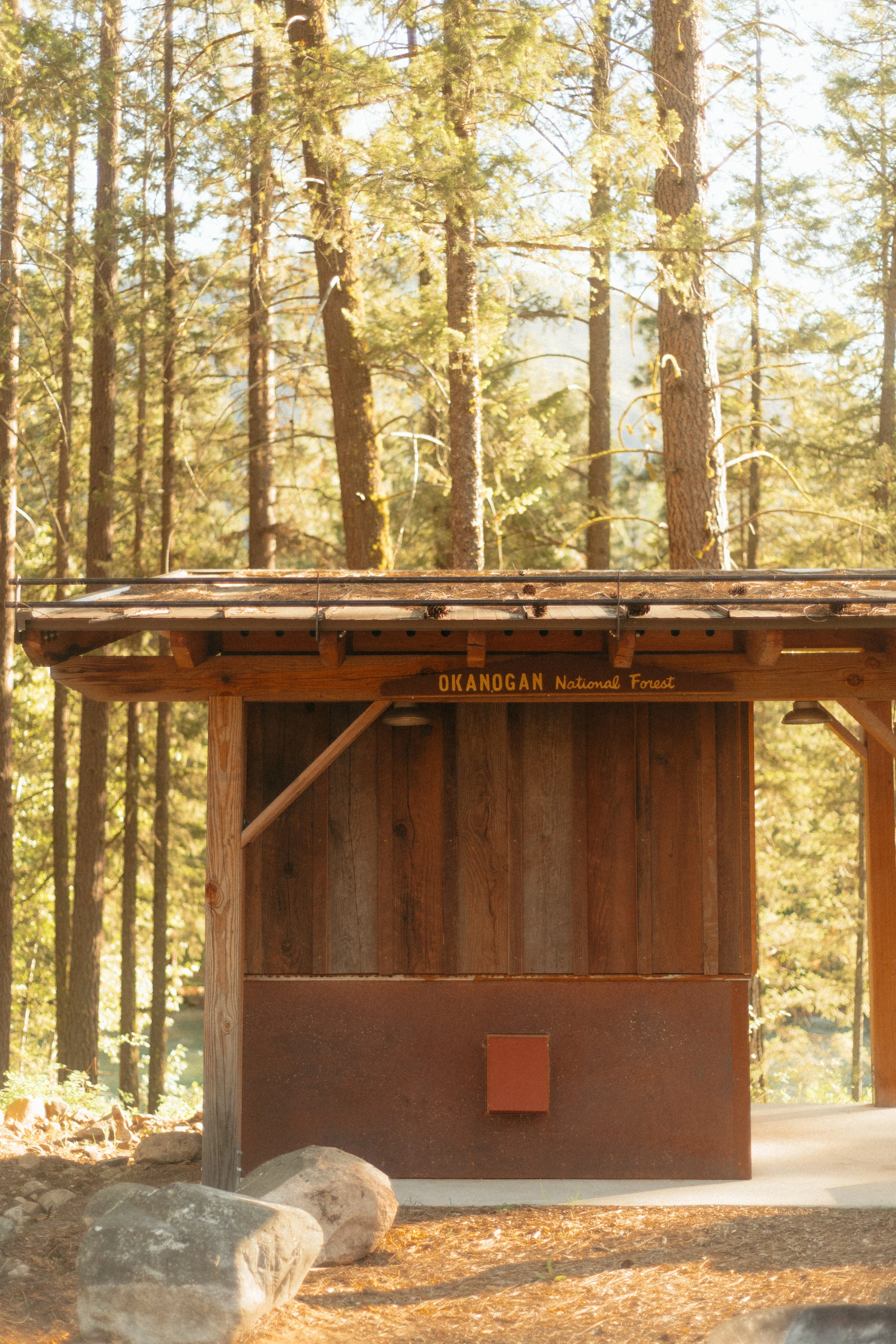Custom sundog sauna with a sign that says 'OKANOGAN National Forest' in a forest setting in the pacific northwest.