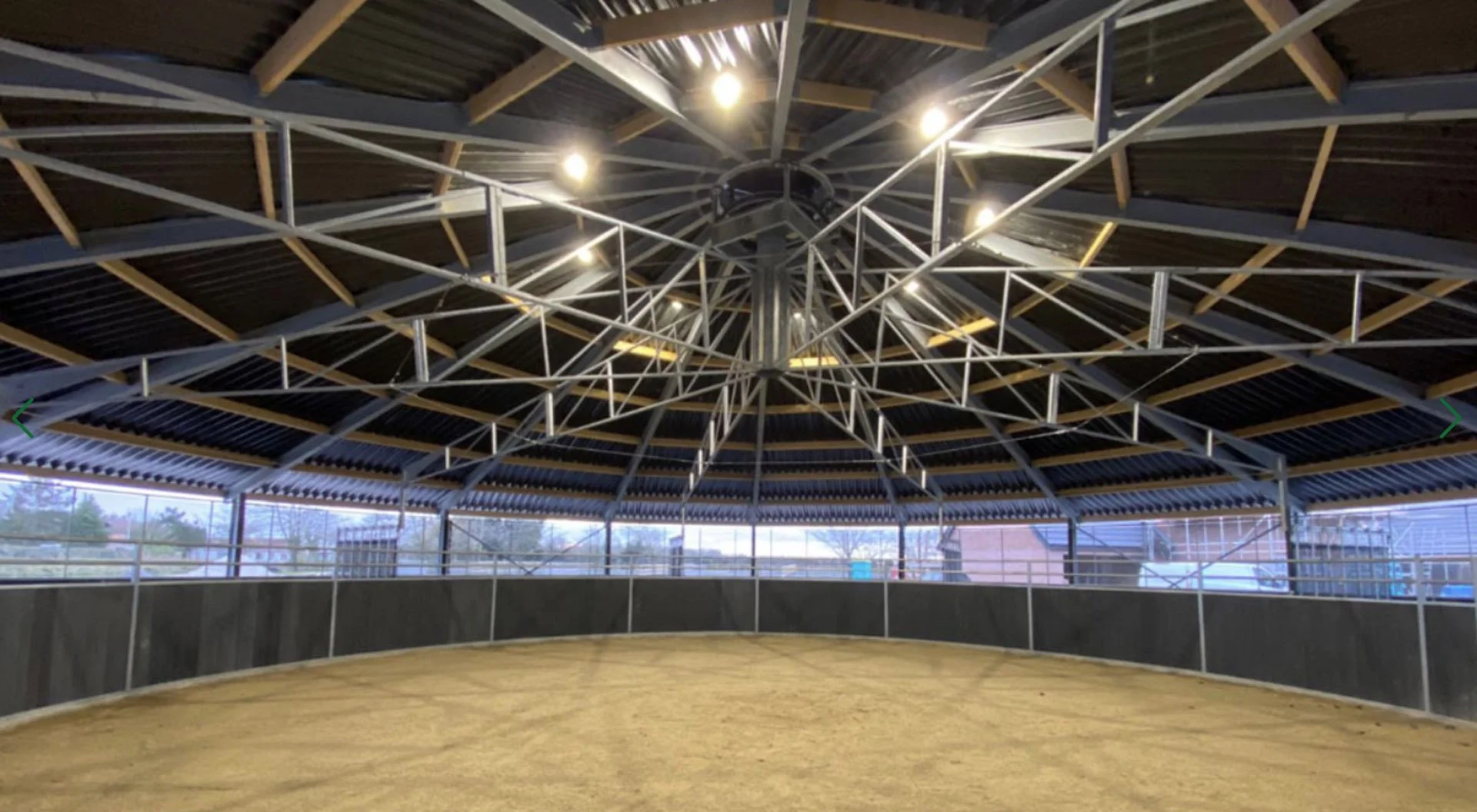 Indoor lunging pen with a horse walker surrounding and a circular metal structure with lights on the ceiling. Available in UAE.