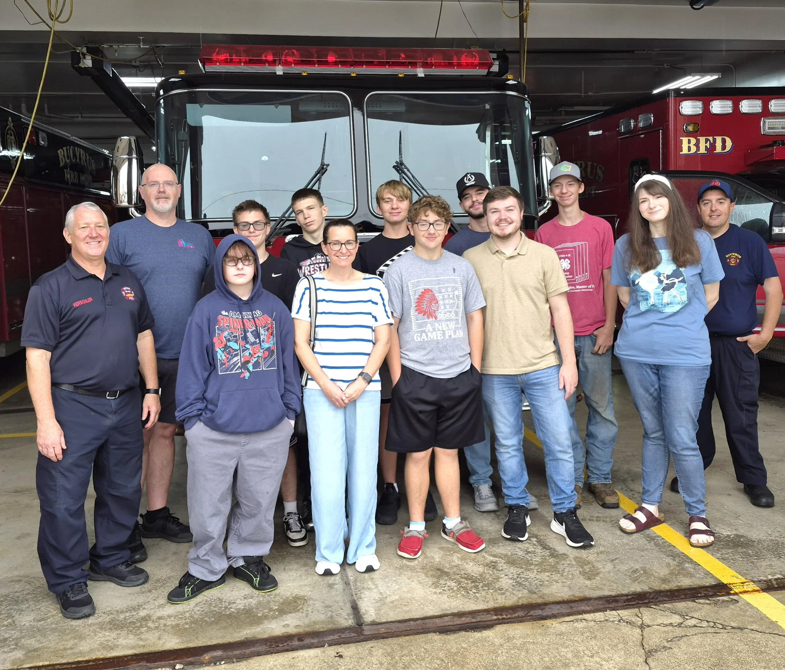 a group of mentors and mentees smiling alongside Bucyrus firemen in front of a parked fire truck