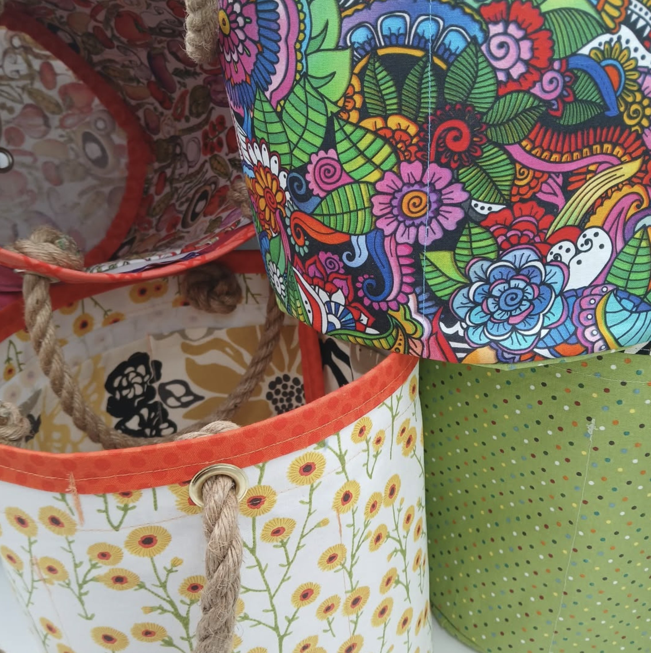 Colorful fabric with floral and leaf patterns, featuring bright colors like pink, green, blue, red, and yellow, and decorated with stitched seams and a woven rope edge.