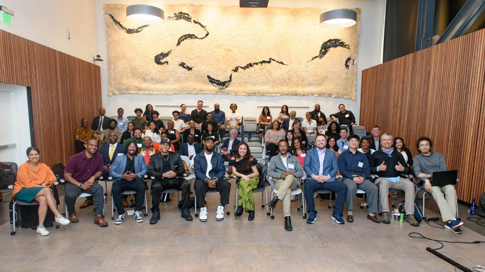 Group photo of diverse people in a conference room with a large textured wall art featuring an abstract map of South America.