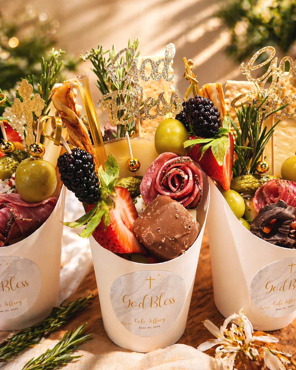 Decorated cups with strawberries, blackberries, green grapes, chocolate, and festive signs reading 'God Bless' and 'Faith' with holiday greenery and flowers.