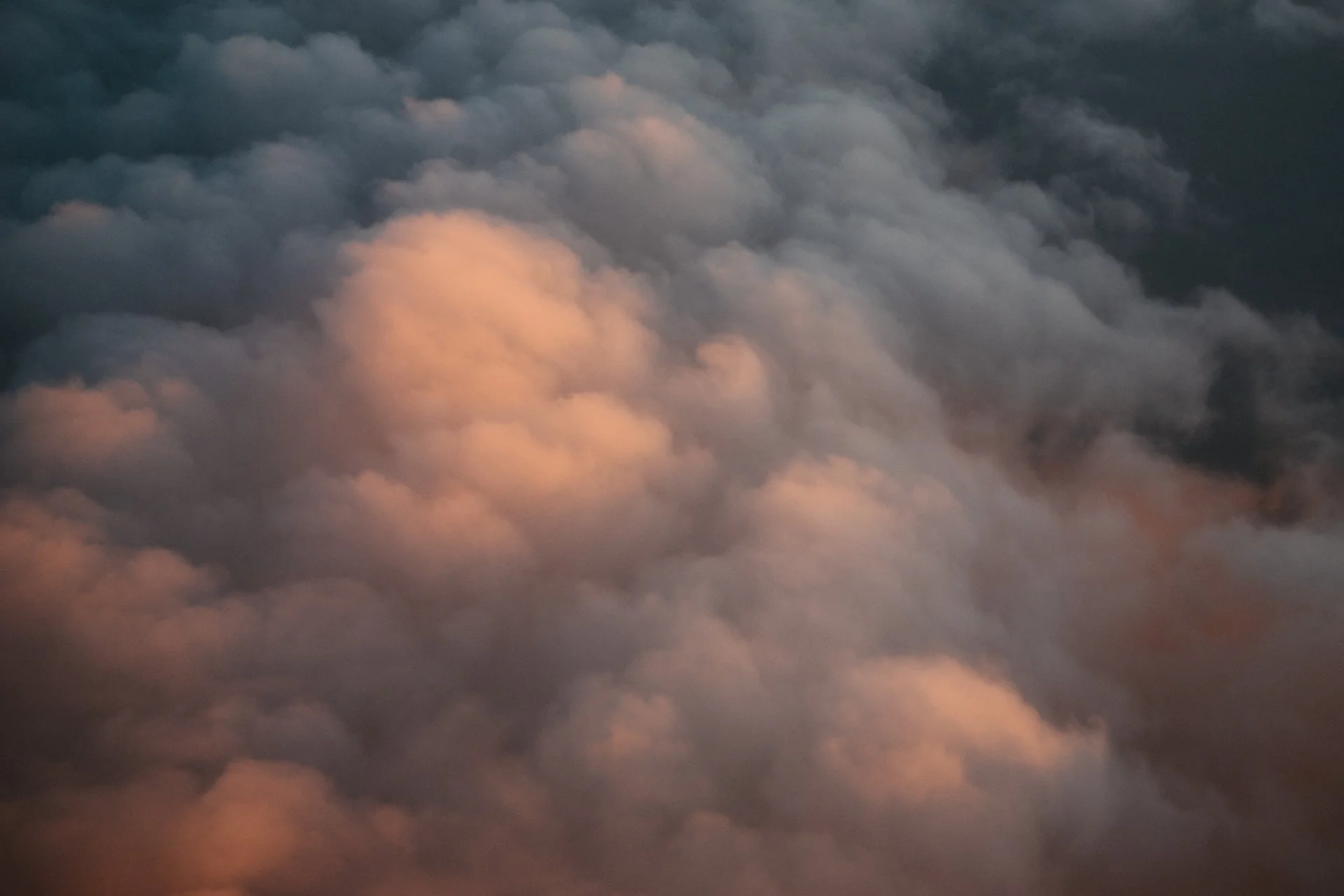 Photo of clouds during sunset or sunrise with pink and dark gray tones.