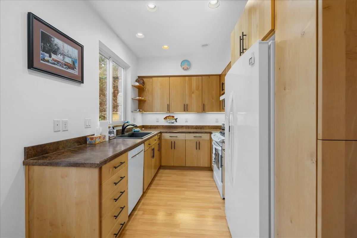 Kitchen with wooden cabinets, white appliances, a window, and a fish-themed decoration.