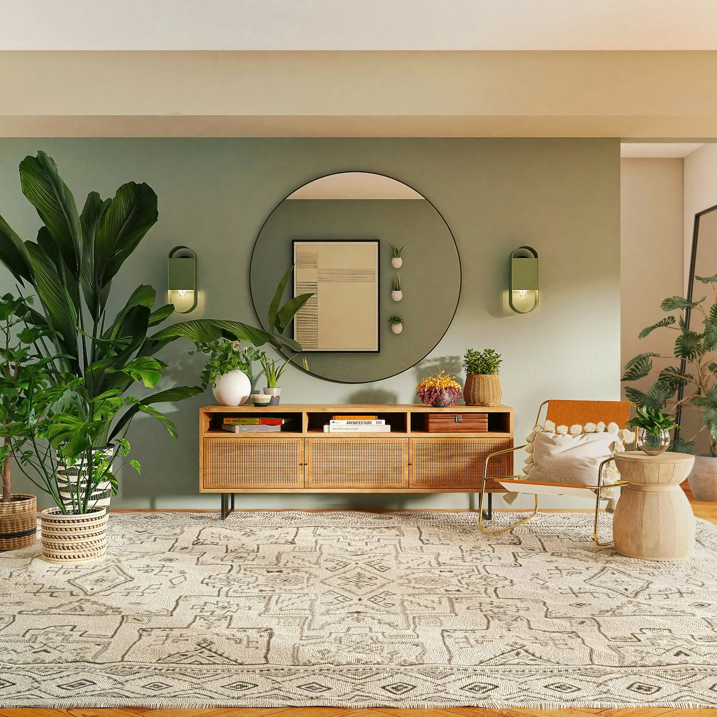 A room with a beige patterned rug, a wooden console table with books and plants, and large green houseplants. The wall behind features a large round mirror, framed artwork, and small wall-mounted planters. A white vase with flowers and a cushioned chair with a throw pillow are also visible.