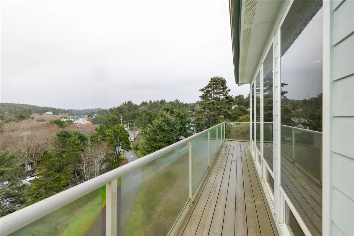 View from a balcony overlooking a green landscape with trees and houses on a cloudy day.