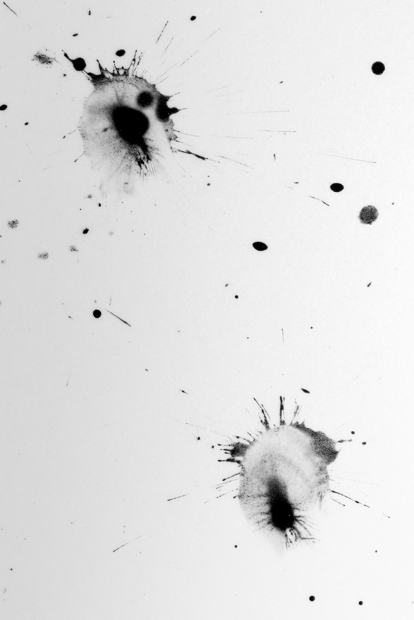 Black ink splatters on white background, resembling abstract inkblots or splashes.