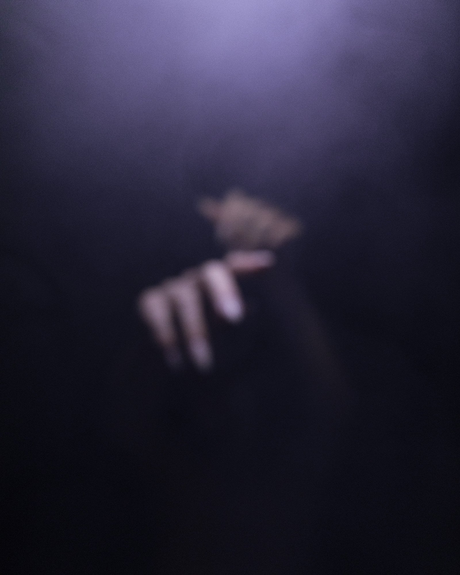 A blurry and foggy close-up of a hands against a dark background.