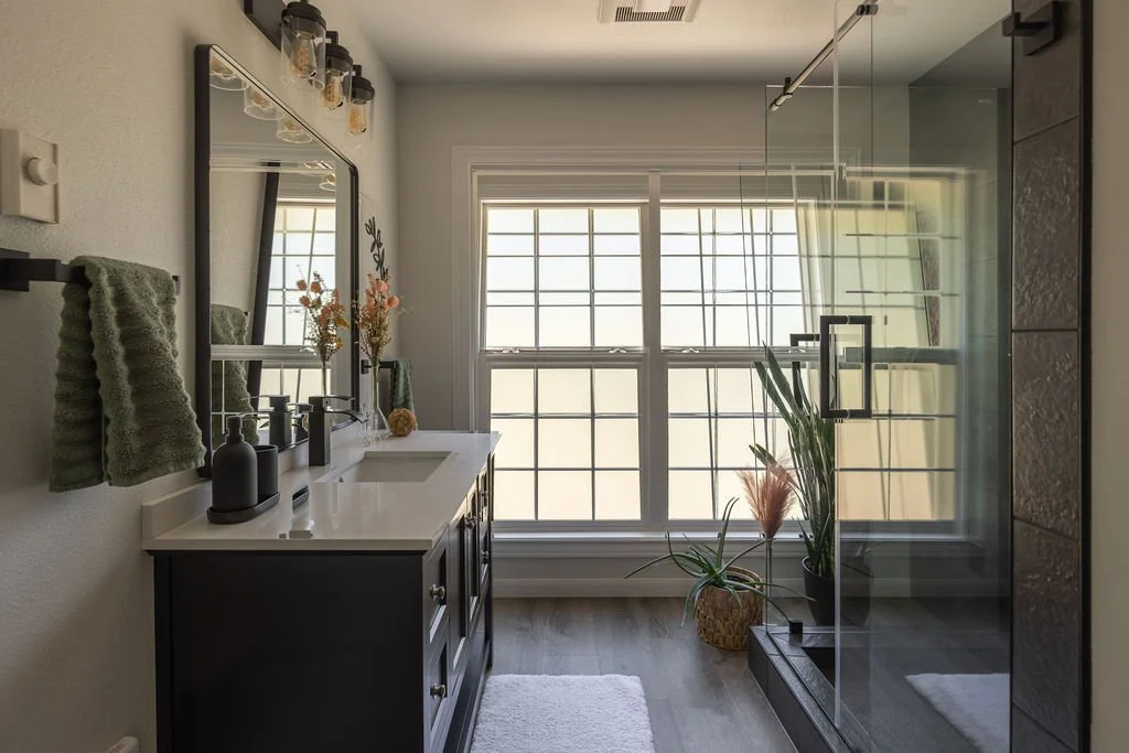 bathroom remodel with walk in shower, floor to ceiling tile, large window with natural light, and free-standing black and white vanity