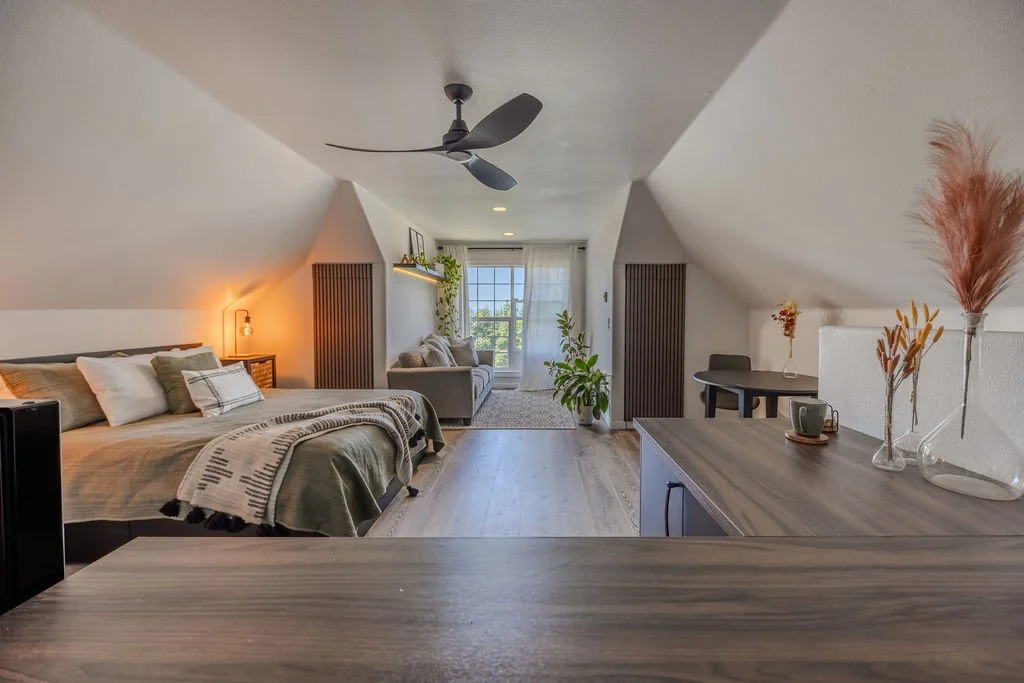 guest loft bedroom and sitting area with sloped ceiling and large window with natural light