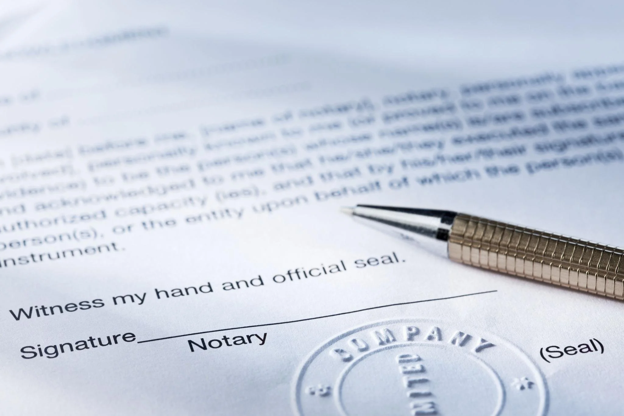 Close-up of a legal document with a signature line, an official seal, and a ballpoint pen resting on the paper.